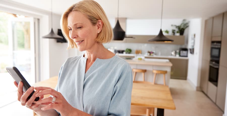 Homeowner holding a mobile device in a room filled with sunlight